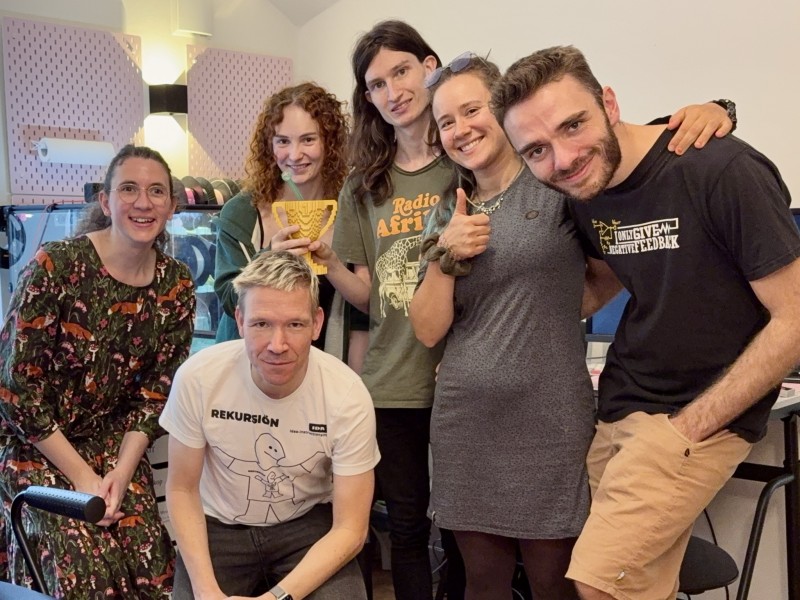 Group picture taken after the Retro-Gaming-Tournament. Six people are looking into the camera smiling, while two people hold up a trophy. 